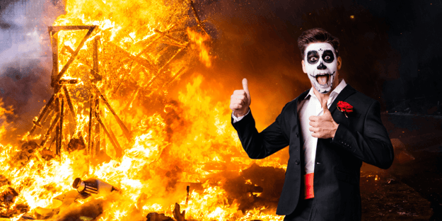 Clown giving a thumbs up and chaos and fire is just behind him